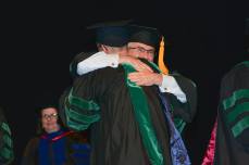 Dr. Tim Stout hugs his graduating son after presenting his hood.